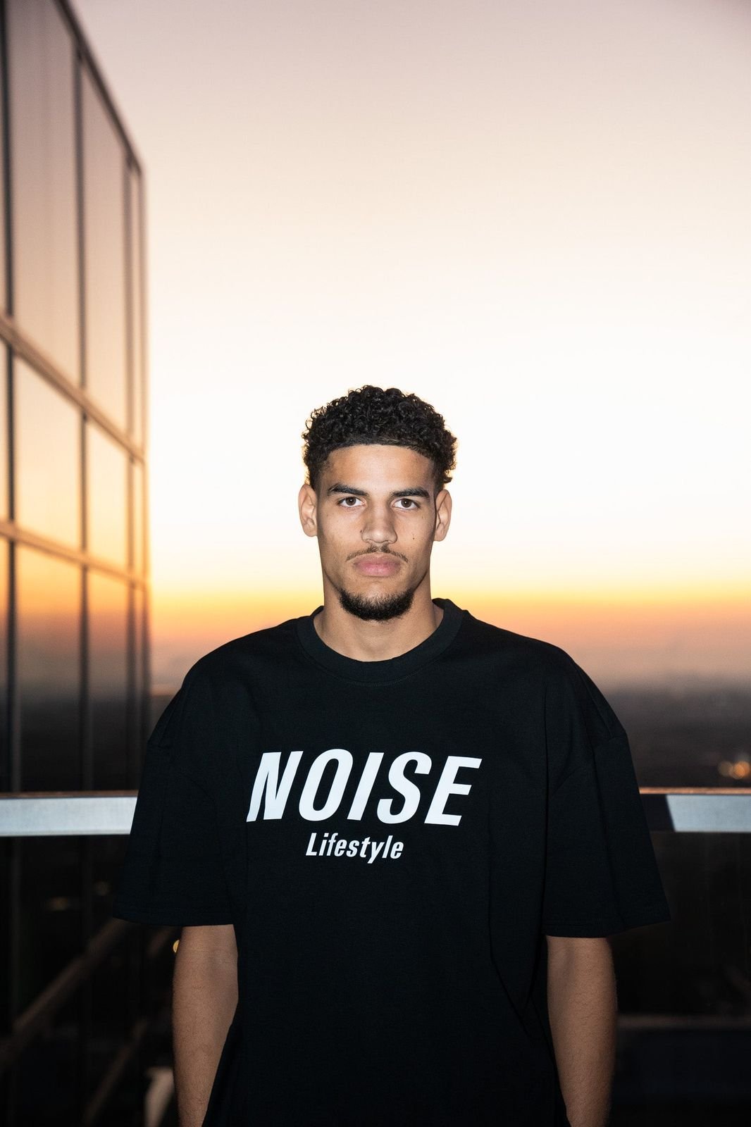 Model in the Noise Logo Tee in black at sunset